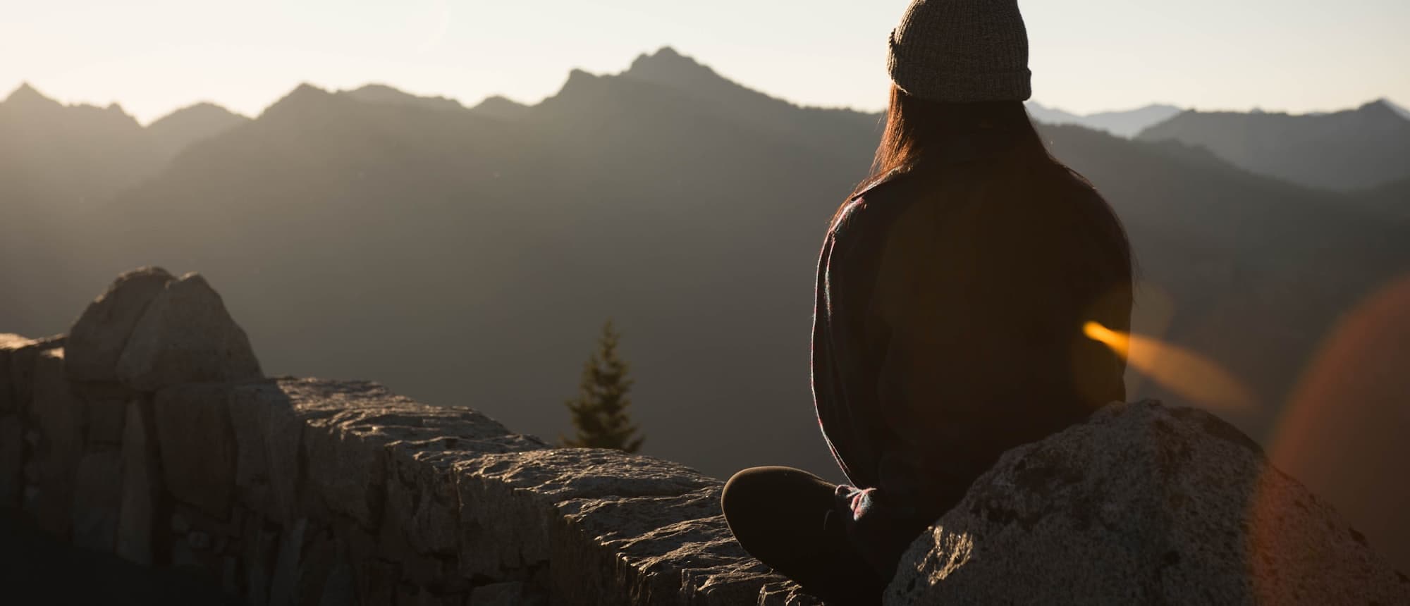 Persona sentada frente a un paisaje de montañas al amanecer
